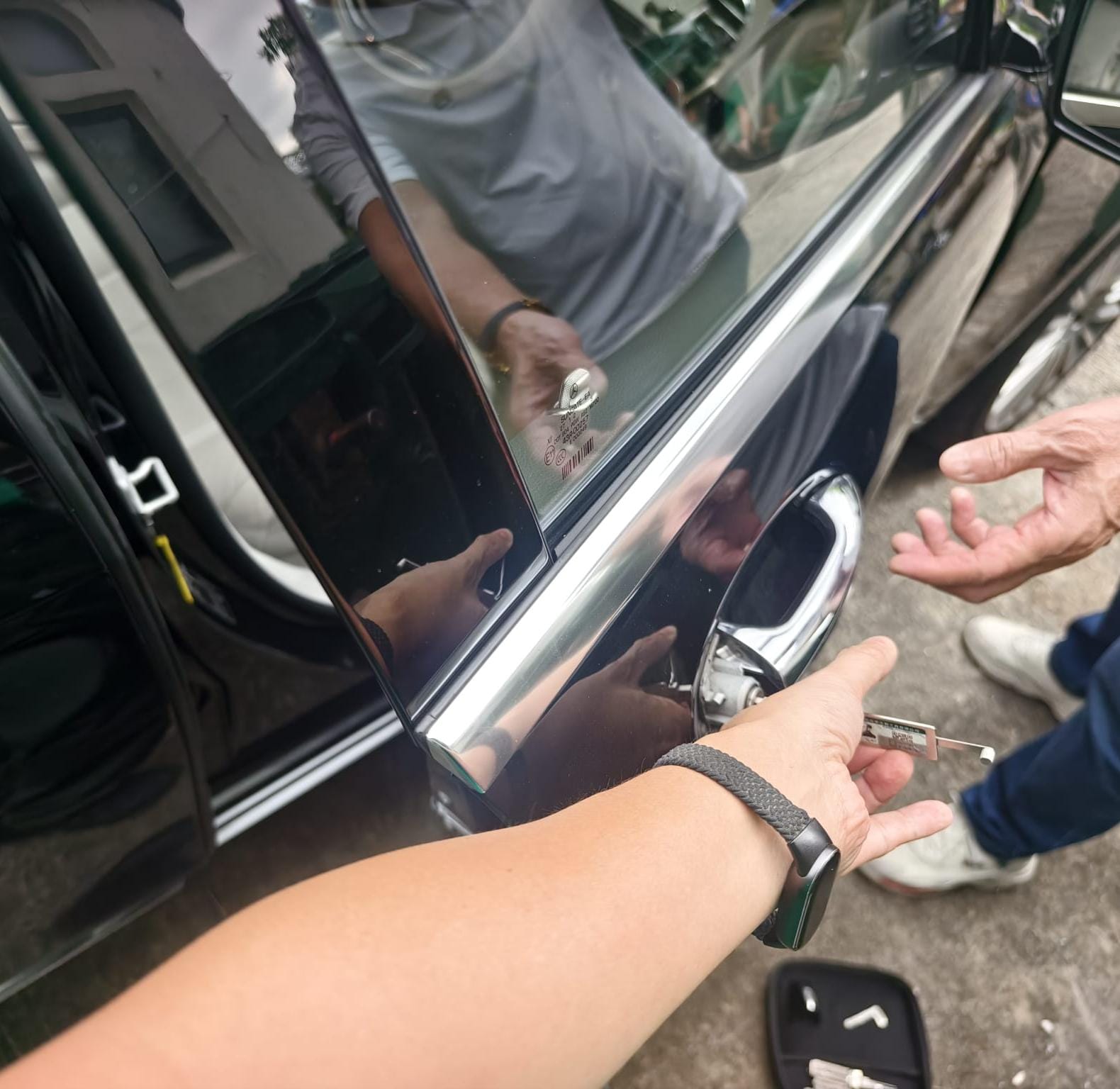 汽車開鎖師傅將專業開鎖工具插入車門鎖芯，車匙遺留車廂內無損取回